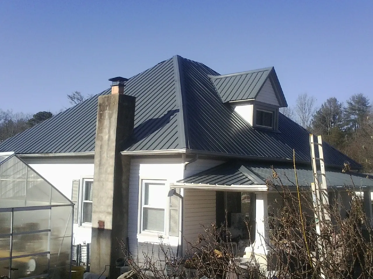 Dark blue standing seam metal roof on a white farmhouse with dormer — Slate & Tile Roof Repair by Roofing Brothers in Chebeague Island