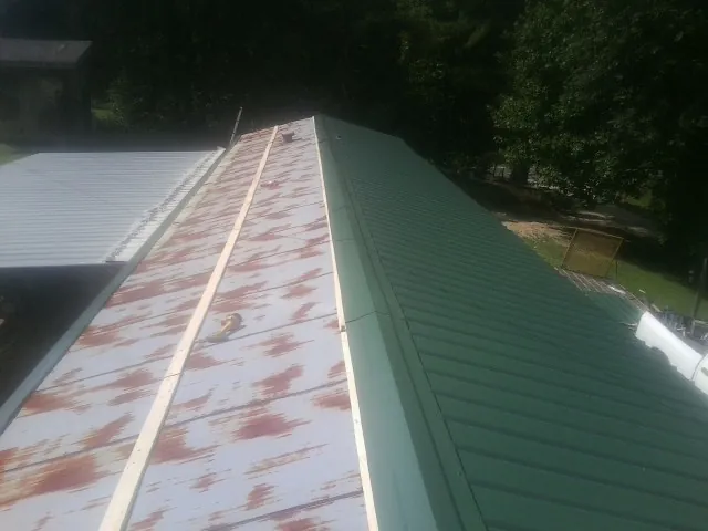 Old rusted panels beside newly installed green metal roofing — Wind Damage Roof Repair by Roofing Brothers in Chebeague Island