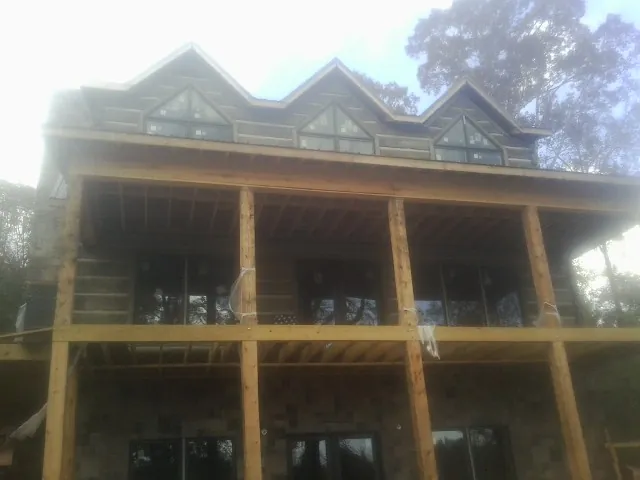 Dormers and porch framing on a large log home under construction — Roof Coating work by our crew in Chebeague Island
