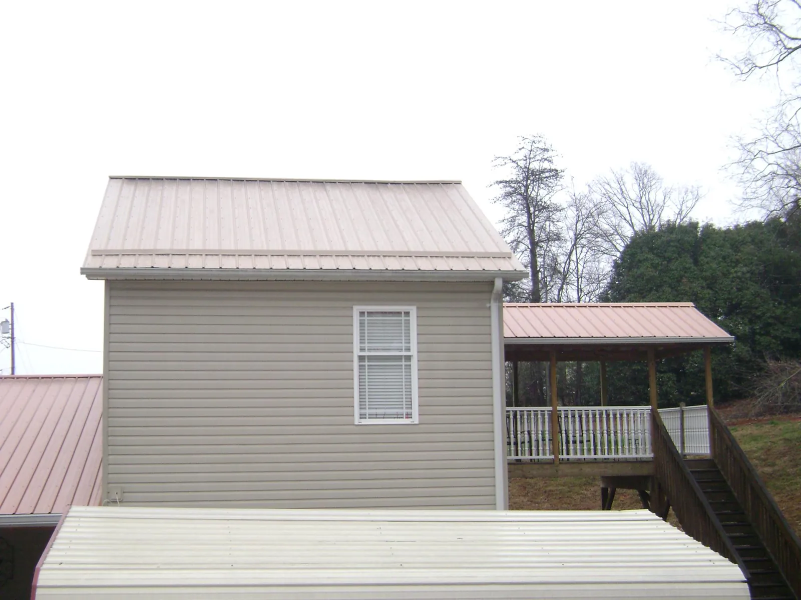 Tan metal roofs on a two story addition and attached porch, from a Roof Replacement job in Chebeague Island