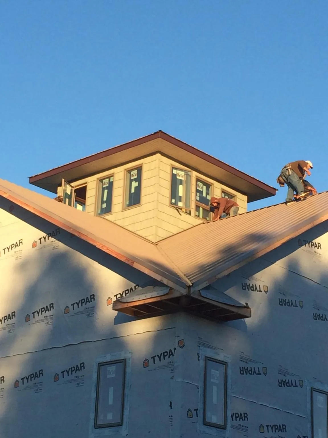 Roofers working around a rooftop cupola on a new metal roof at sunset — Roof Waterproofing in Chebeague Island by Roofing Brothers
